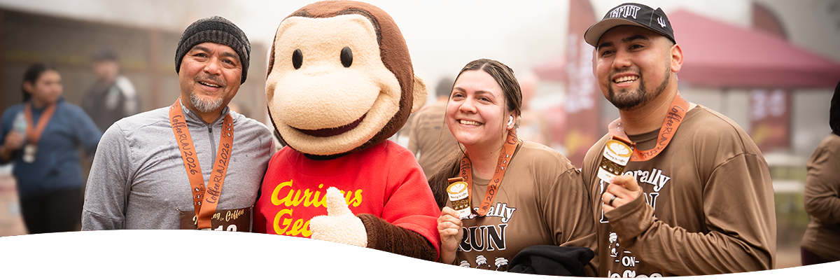 Curious George standing with runners holding medals